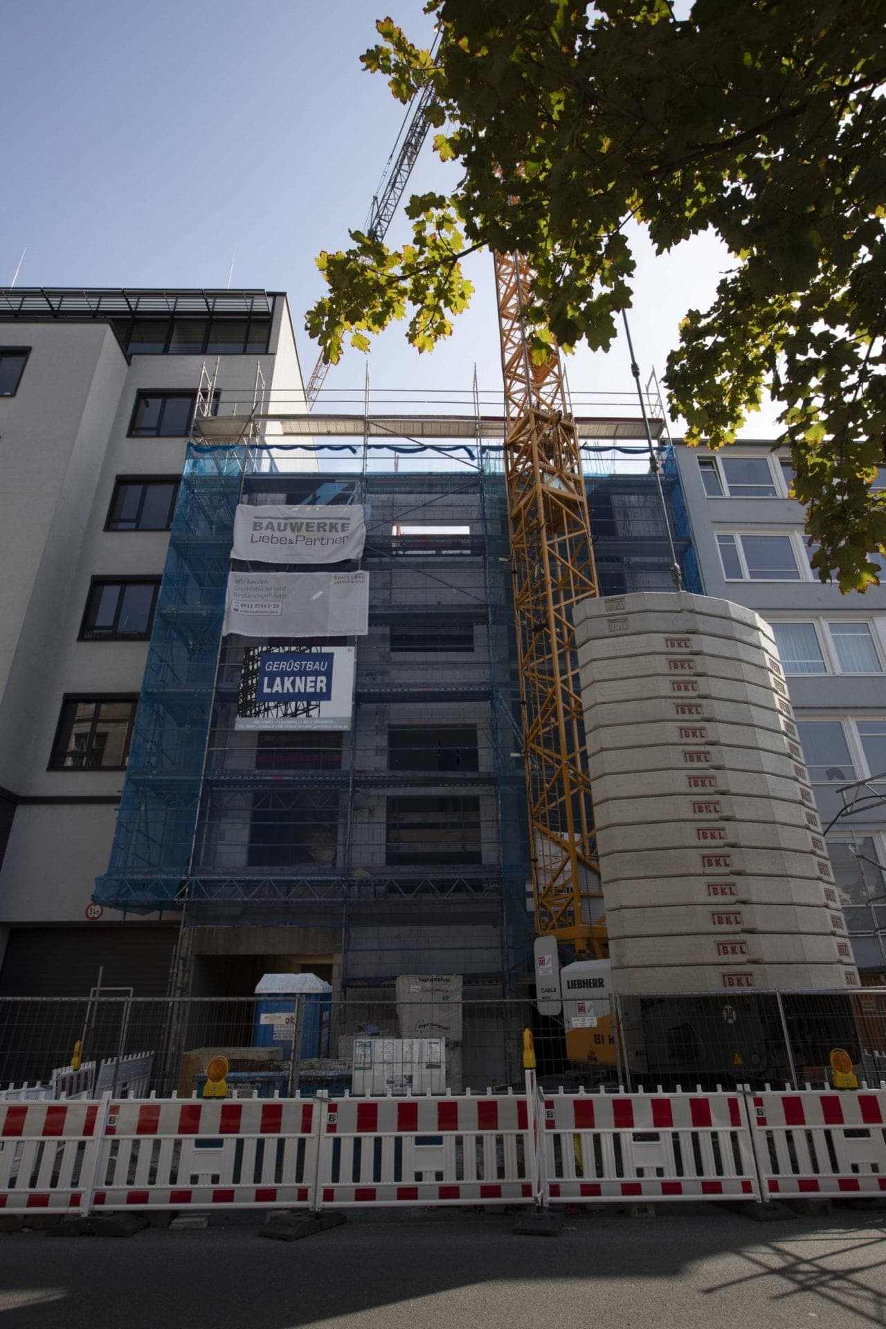 Scaffolded shell with site boards and a tower crane on Flaschenhofstraße, seen from below
