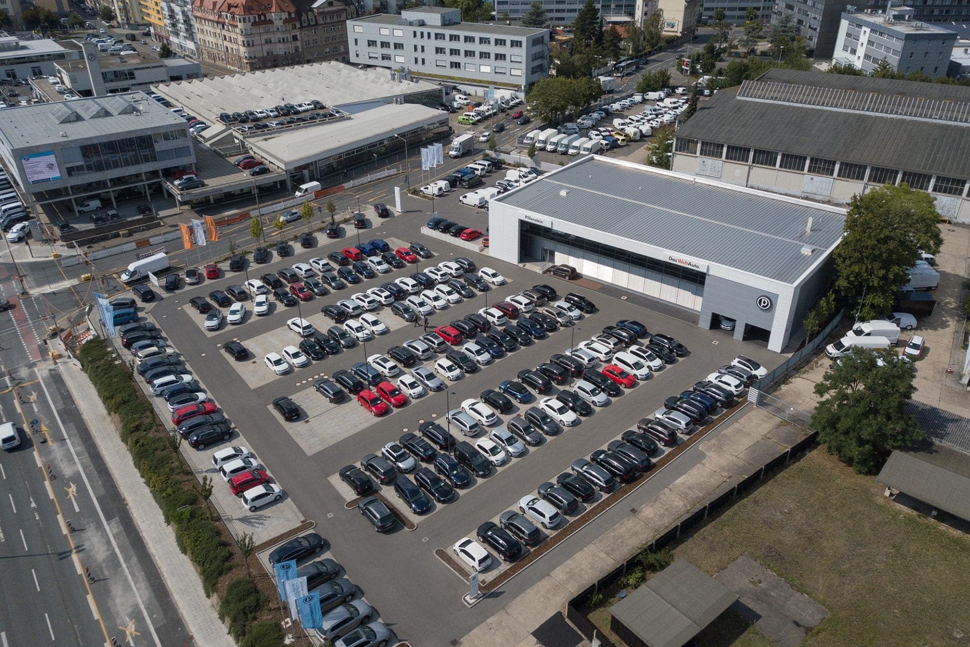 Aerial view of the display area with numerous vehicles parked in rows in front of the dealership