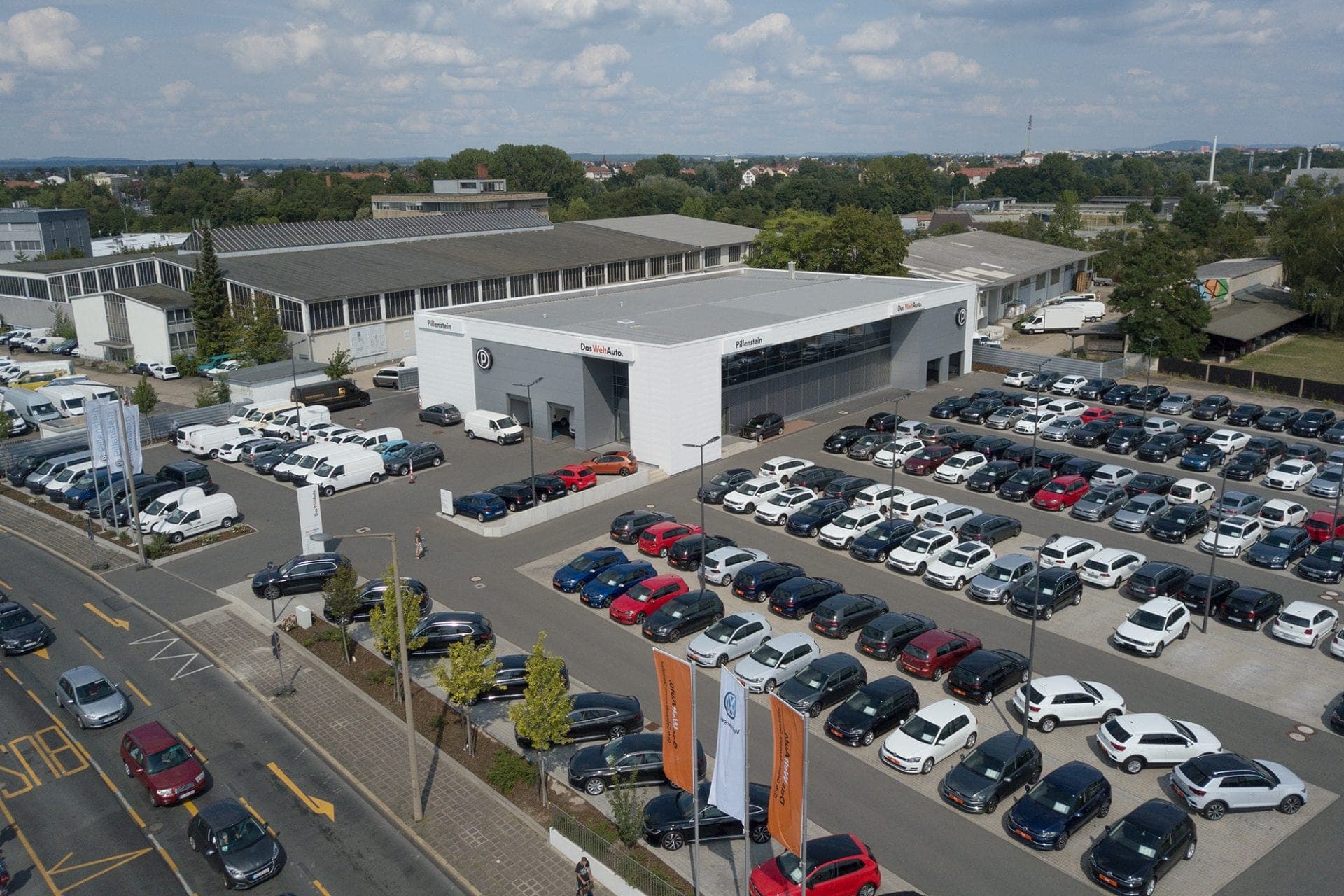 Oblique aerial view of the dealership with the roadside display area and commercial buildings beyond