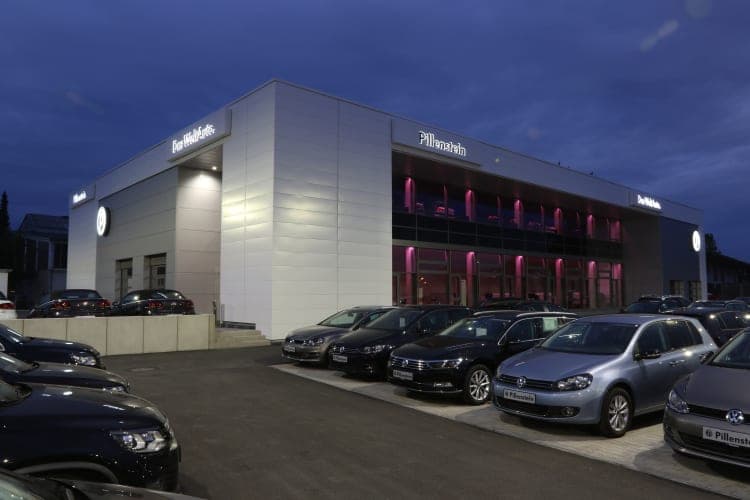 Showroom façade at dusk with the Pillenstein lettering and the interior lit in pink