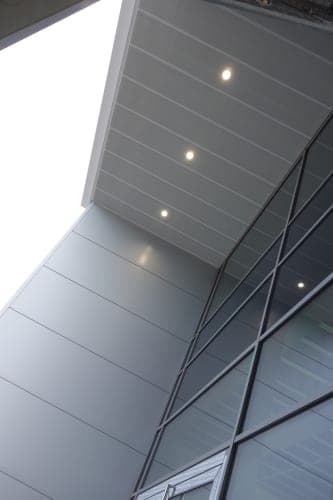 Upward view of the canopy soffit with recessed lights above the metal cassette cladding and glazing