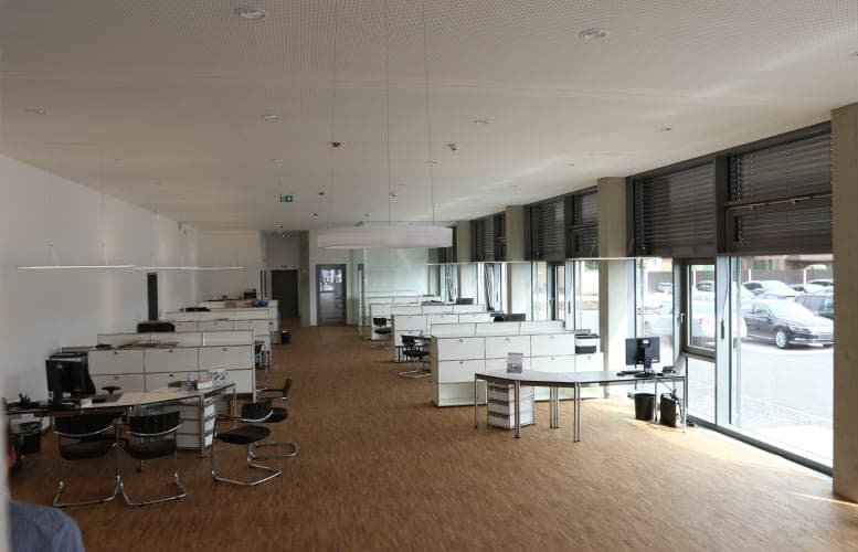 Customer area with open workstations, parquet flooring and a floor-to-ceiling window front onto the forecourt