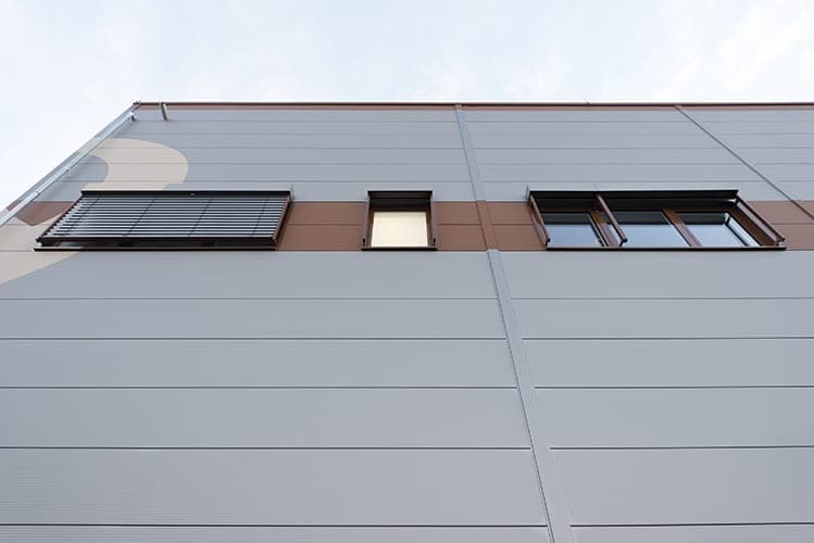 Looking up the pale hall façade to a brown window band with an external blind