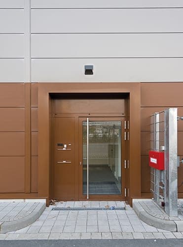 Side entrance to the production hall with brown metal cladding and a glazed door