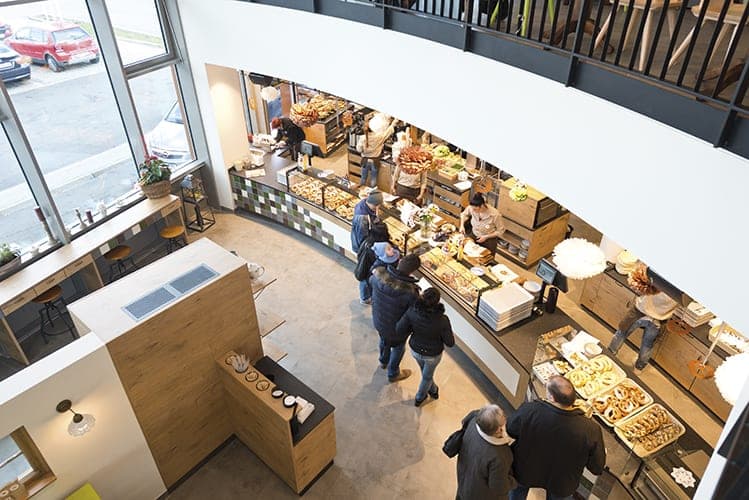 View from the gallery down to the sales counter with baked goods and waiting customers