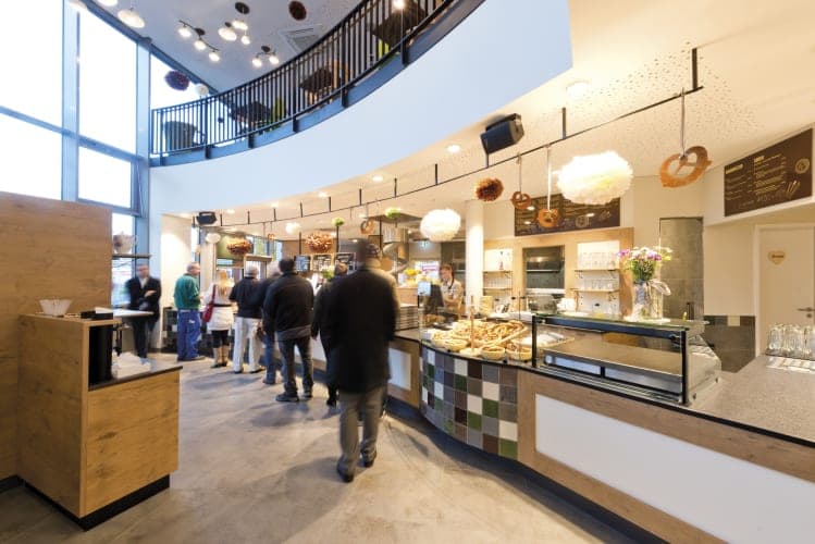 Shop interior with a curved counter and the first-floor gallery of the café