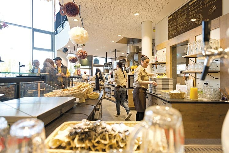 View along the sales counter with staff, baskets of pretzels and hanging decorations