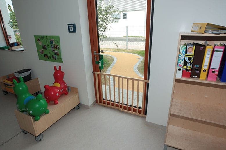 View from a group room through the open door with a wooden safety gate onto a curving garden path
