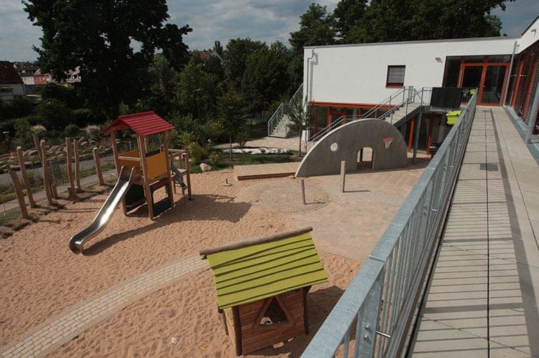 View from the access gallery over the sand playground with slide tower, play hut and concrete arch
