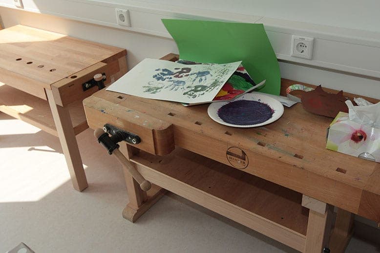Carpenter's workbench in the craft room with handprint paintings, a paint plate and craft materials