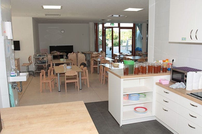 Dining area with children's tables and a serving counter, glazed doors to the garden beyond