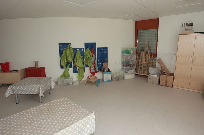 Art studio with painting smocks on blue pegboards, covered tables and craft materials