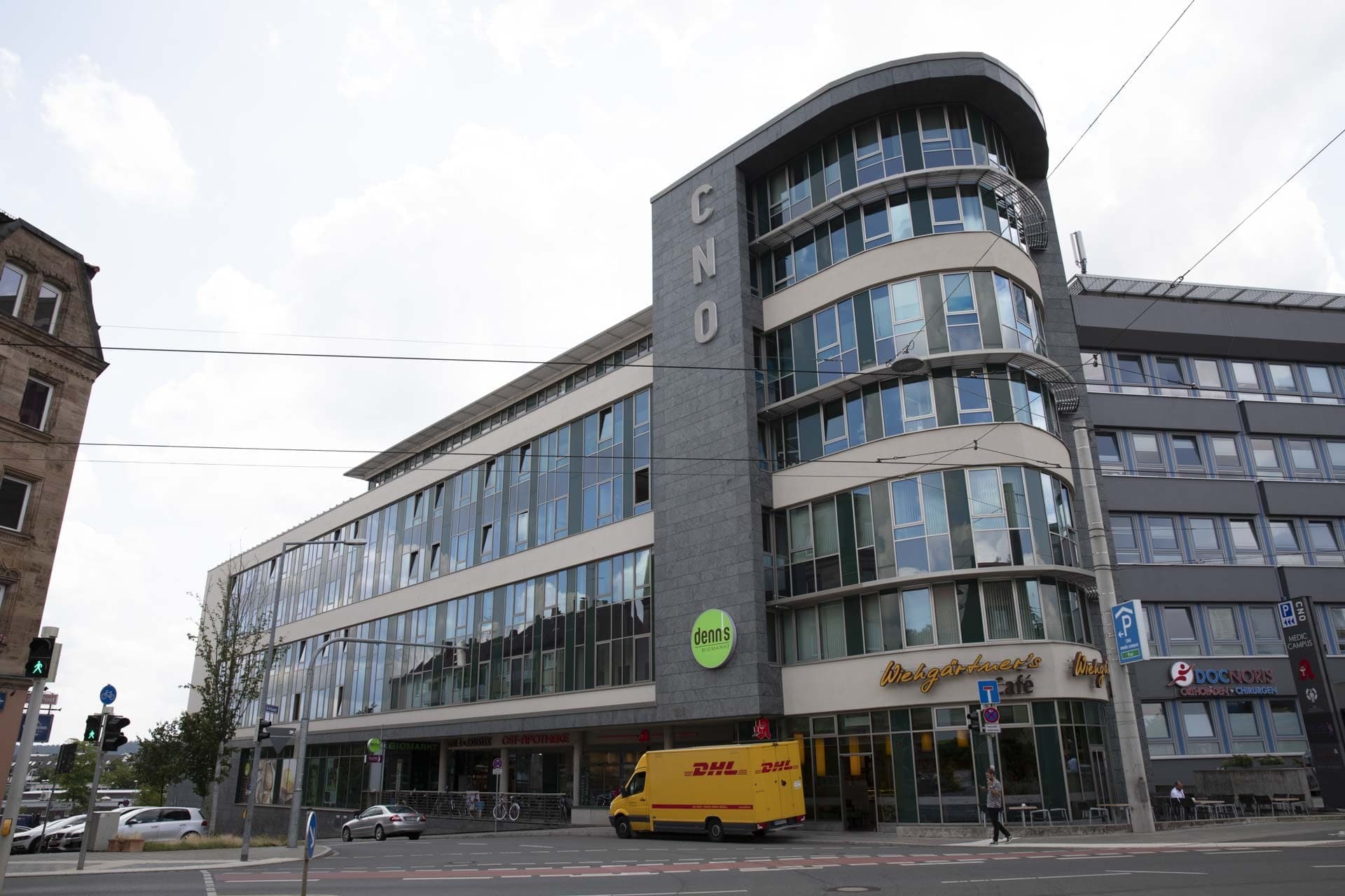 Straßenecke in Nürnberg mit dem sechsgeschossigen Neubau, Glasbändern, Natursteinpfeiler und Café im Erdgeschoss