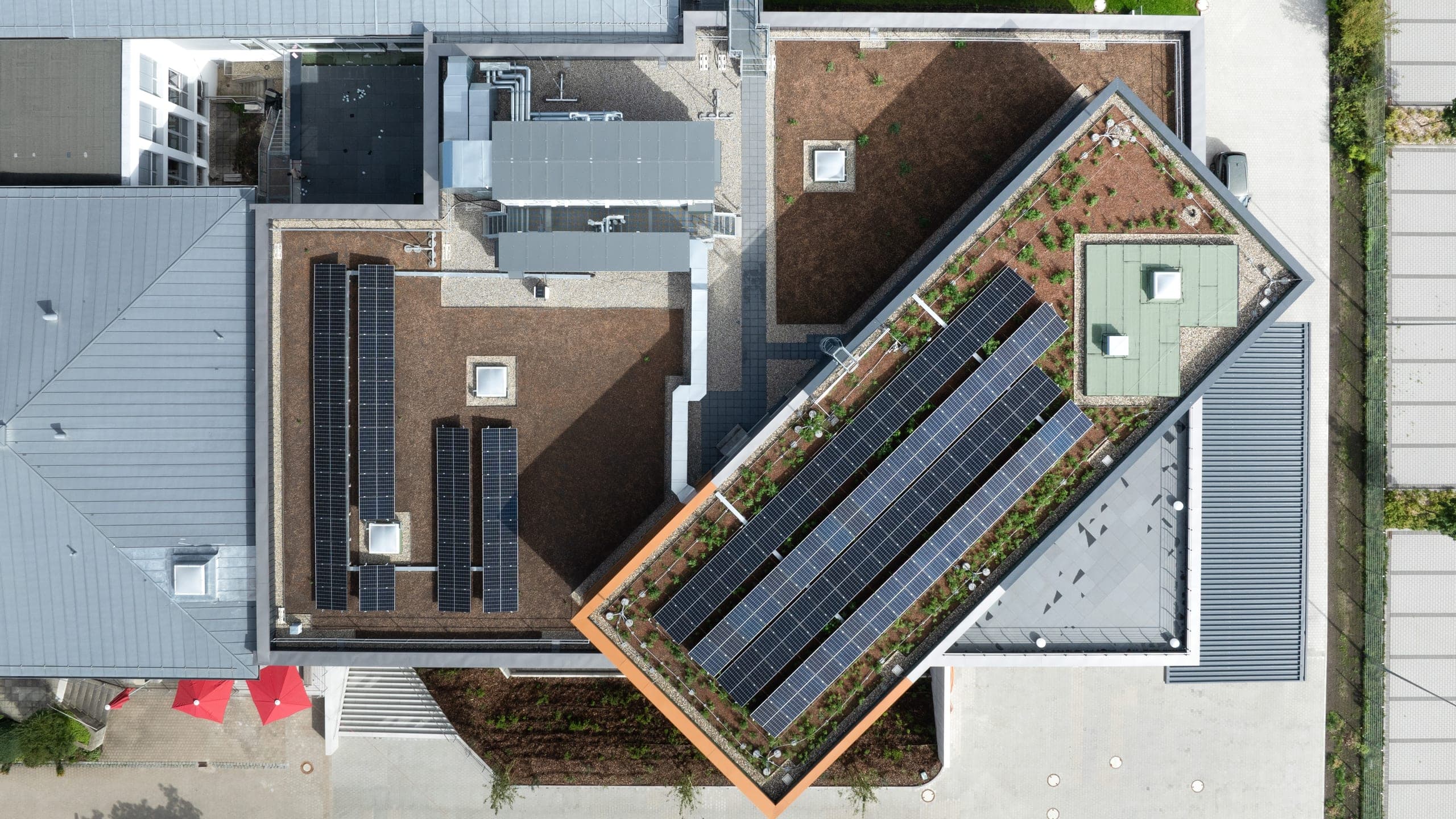 Senkrechte Draufsicht auf das Gründach mit Photovoltaikreihen, Oberlichtern und Haustechnikaufbauten
