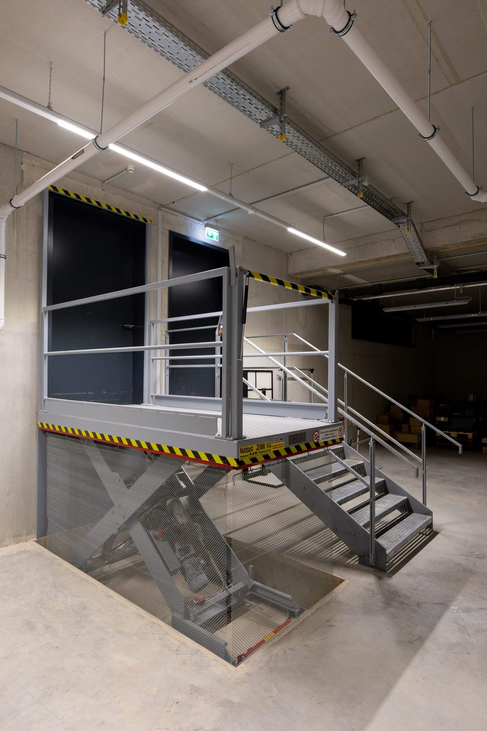 Hebebühne mit Stahltreppe und Geländer im Lagerbereich der Pinselmanufaktur