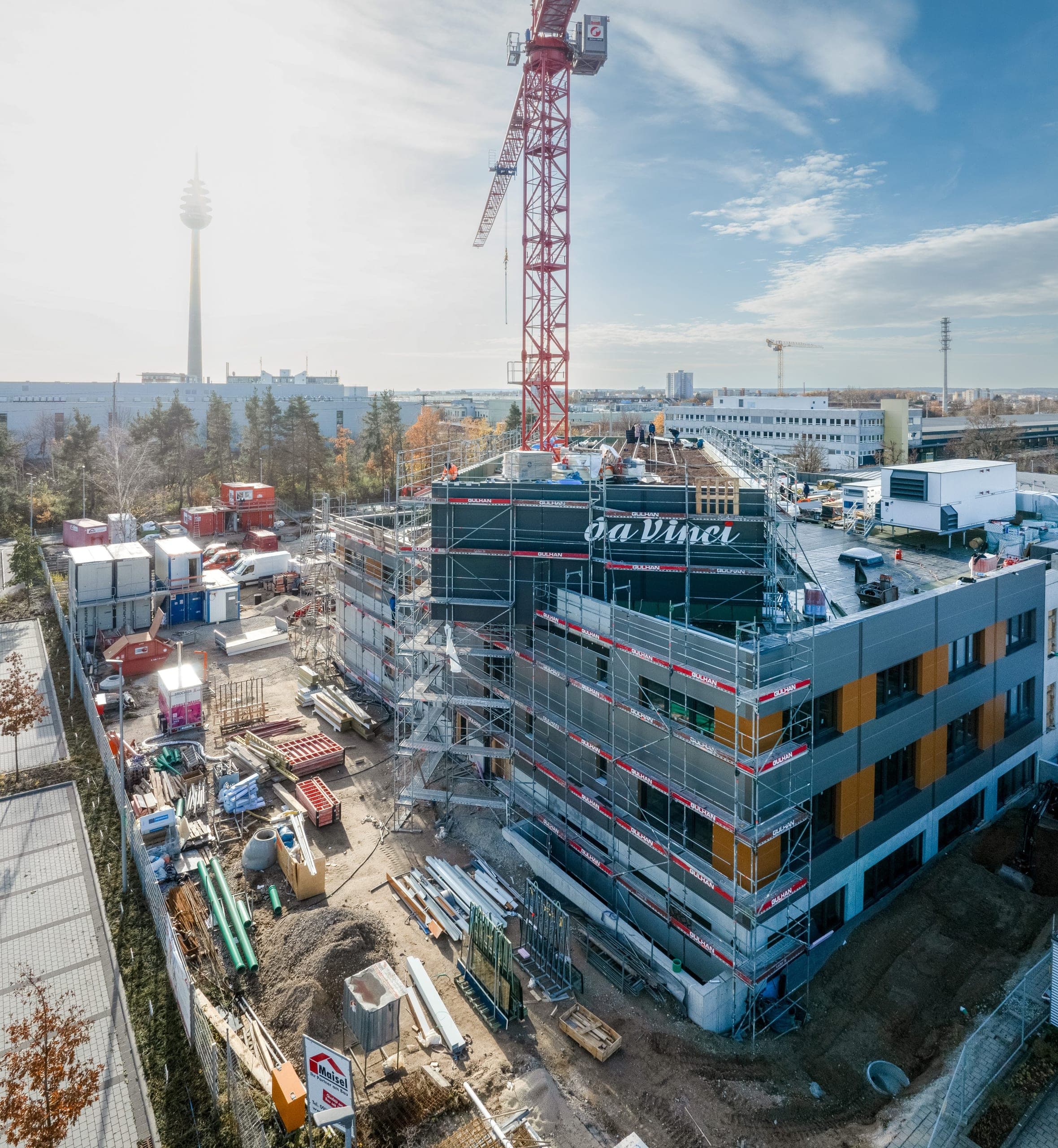 Baustelle aus der Luft mit Turmkran, Lagerflächen und Fernmeldeturm am Horizont