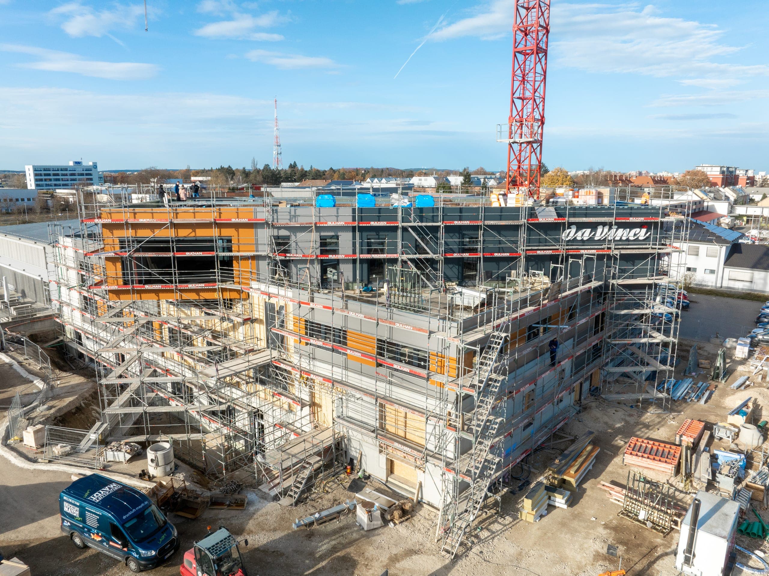 Eingerüsteter Rohbau mit orangefarbenen Fassadenfeldern während der Bauphase in Nürnberg