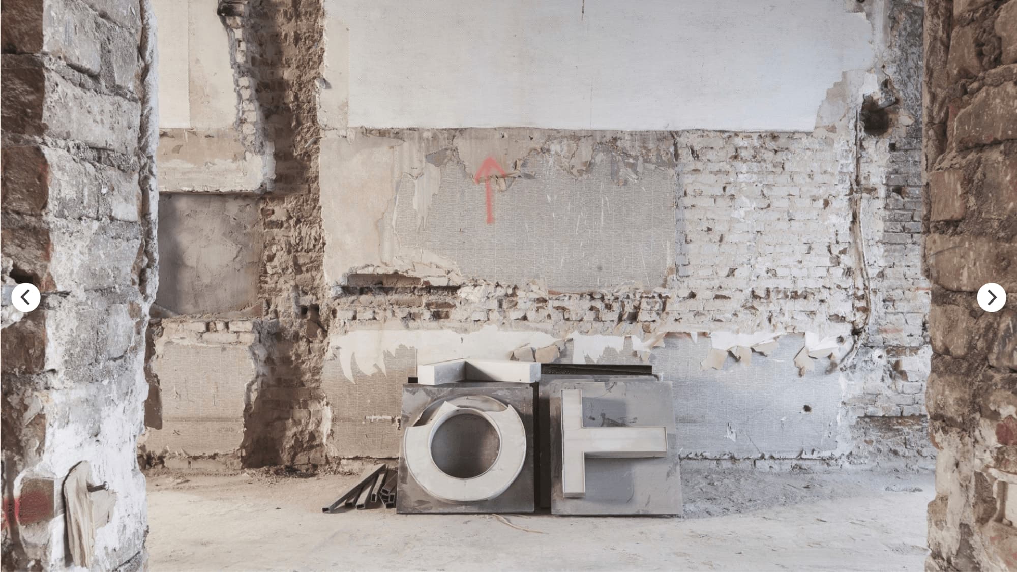 Stripped-out room with exposed masonry and two removed illuminated letters standing on the floor