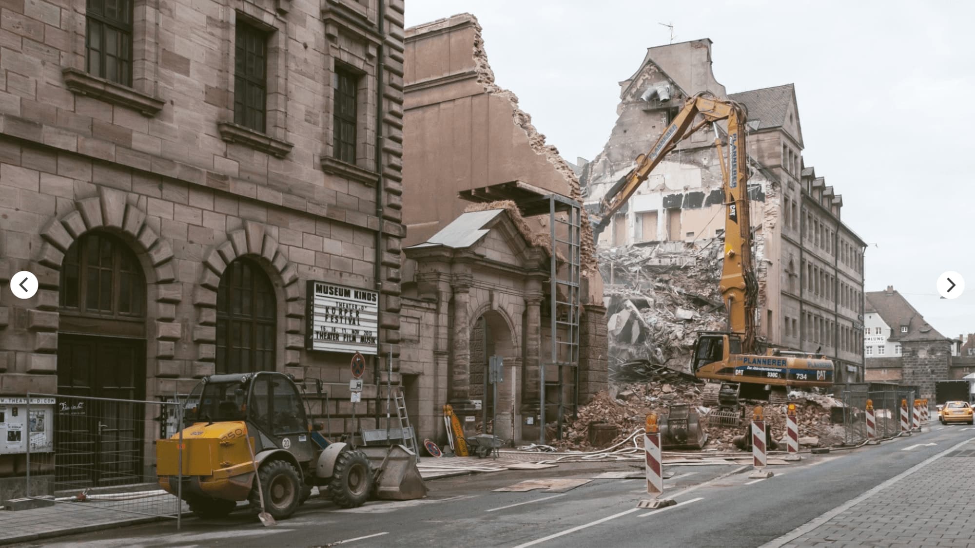 Demolition with an excavator behind the historic gateway in Nuremberg, with the arched sandstone building on the left