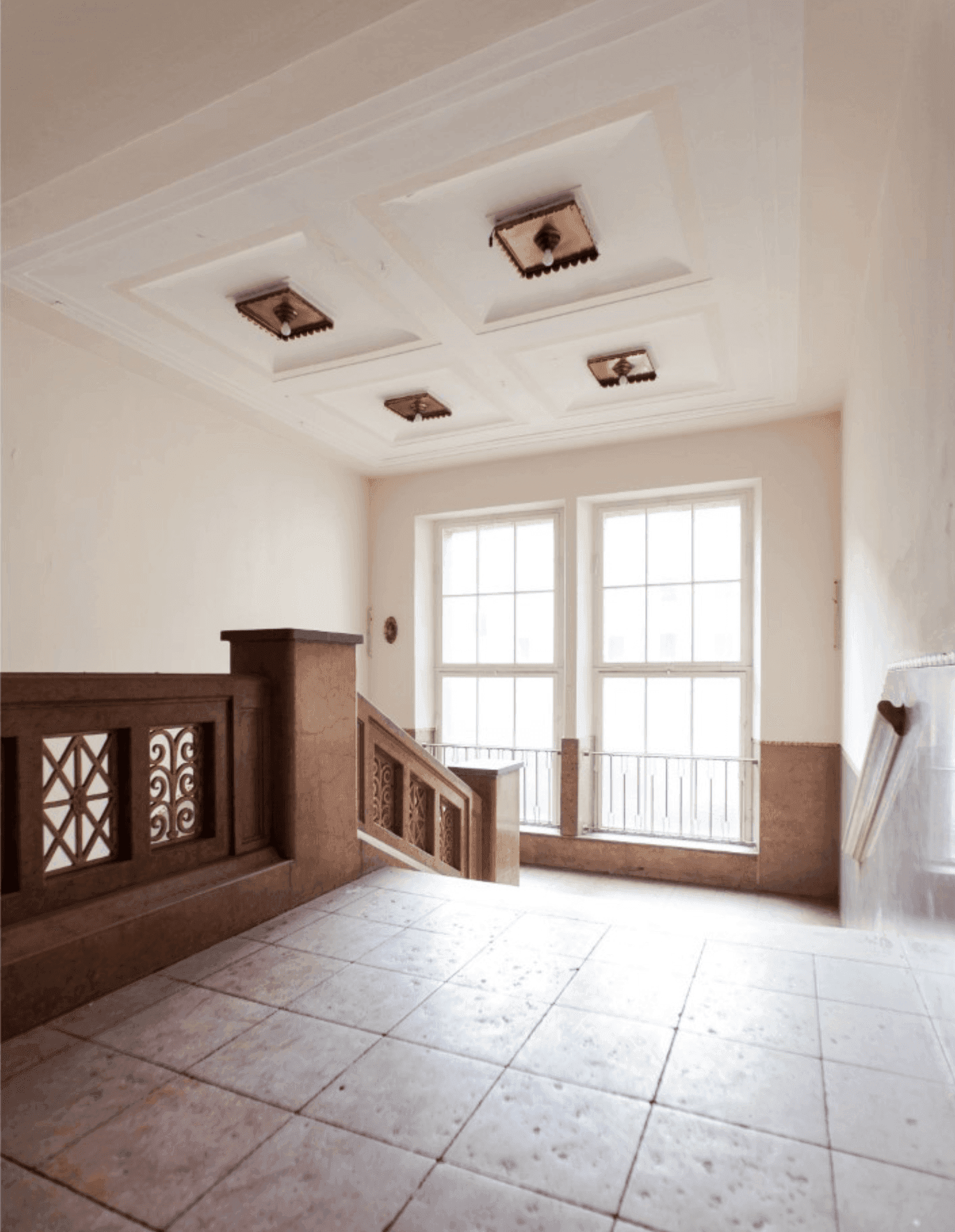 Refurbished staircase with a coffered ceiling, a stone balustrade with ornamental grilles and tall glazing-bar windows