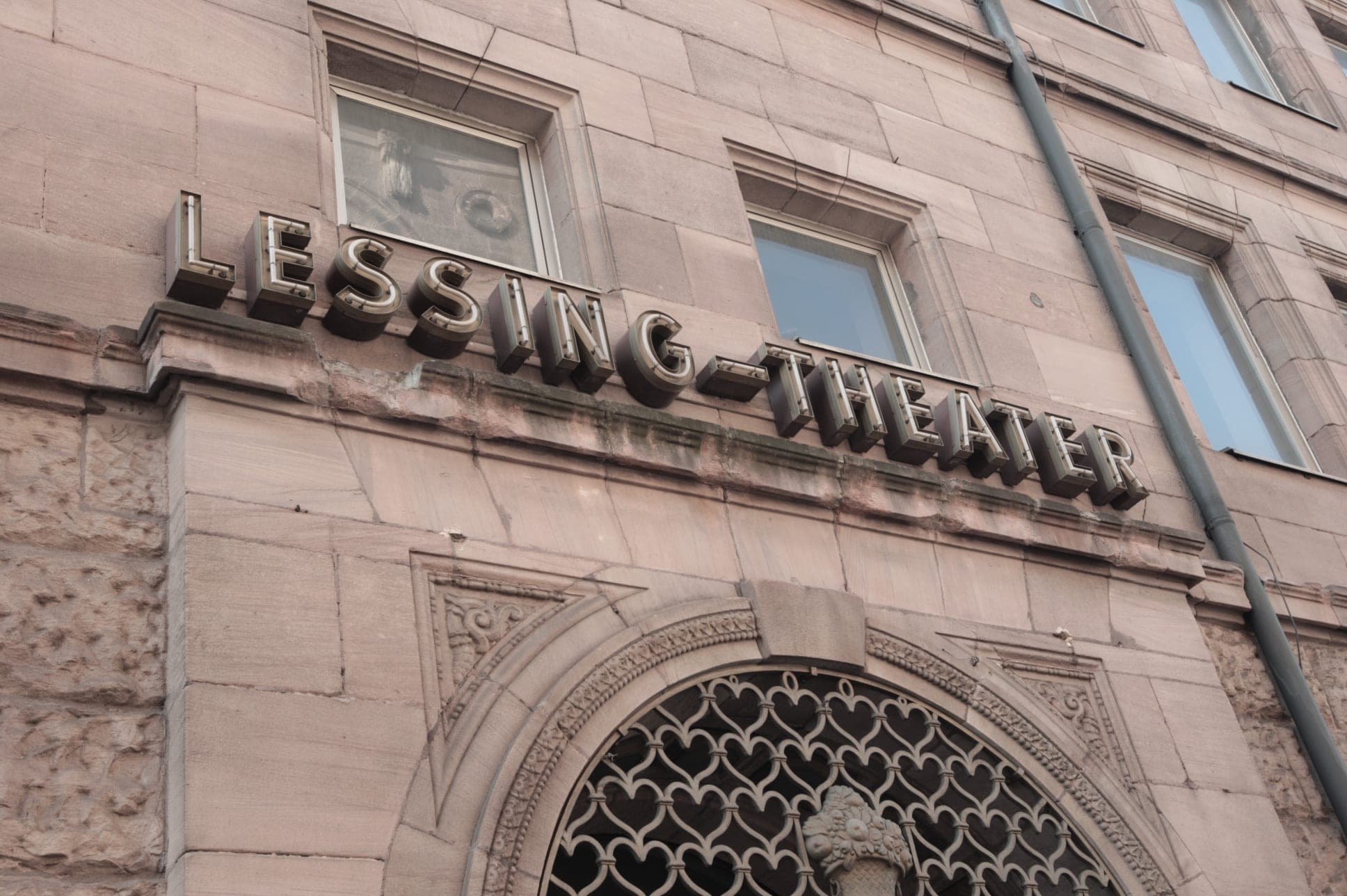 Historic Lessing-Theater lettering above a round arch with an ornamental grille on the sandstone façade
