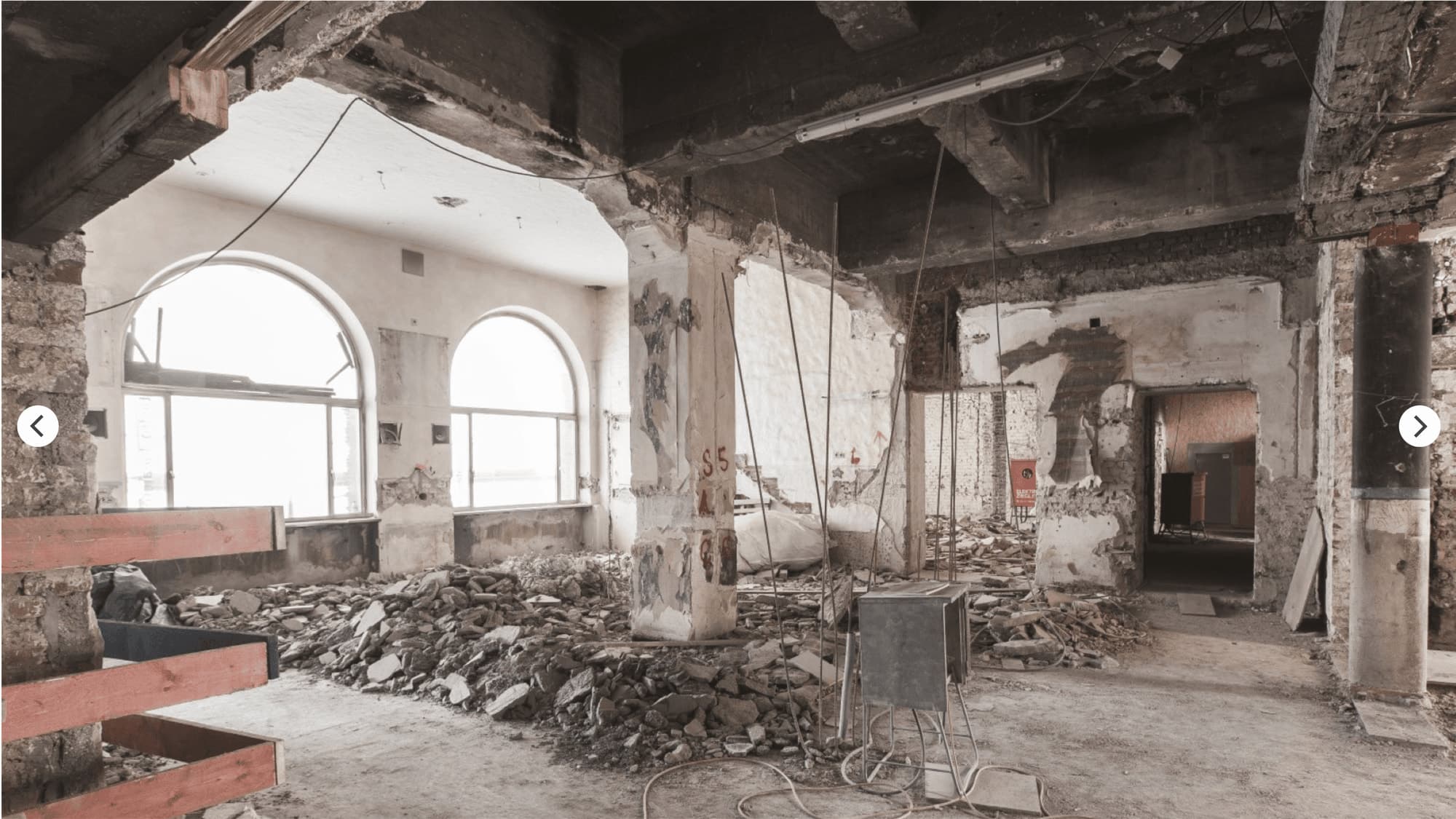 Strip-out with piles of rubble, exposed columns and tall arched windows during the refurbishment