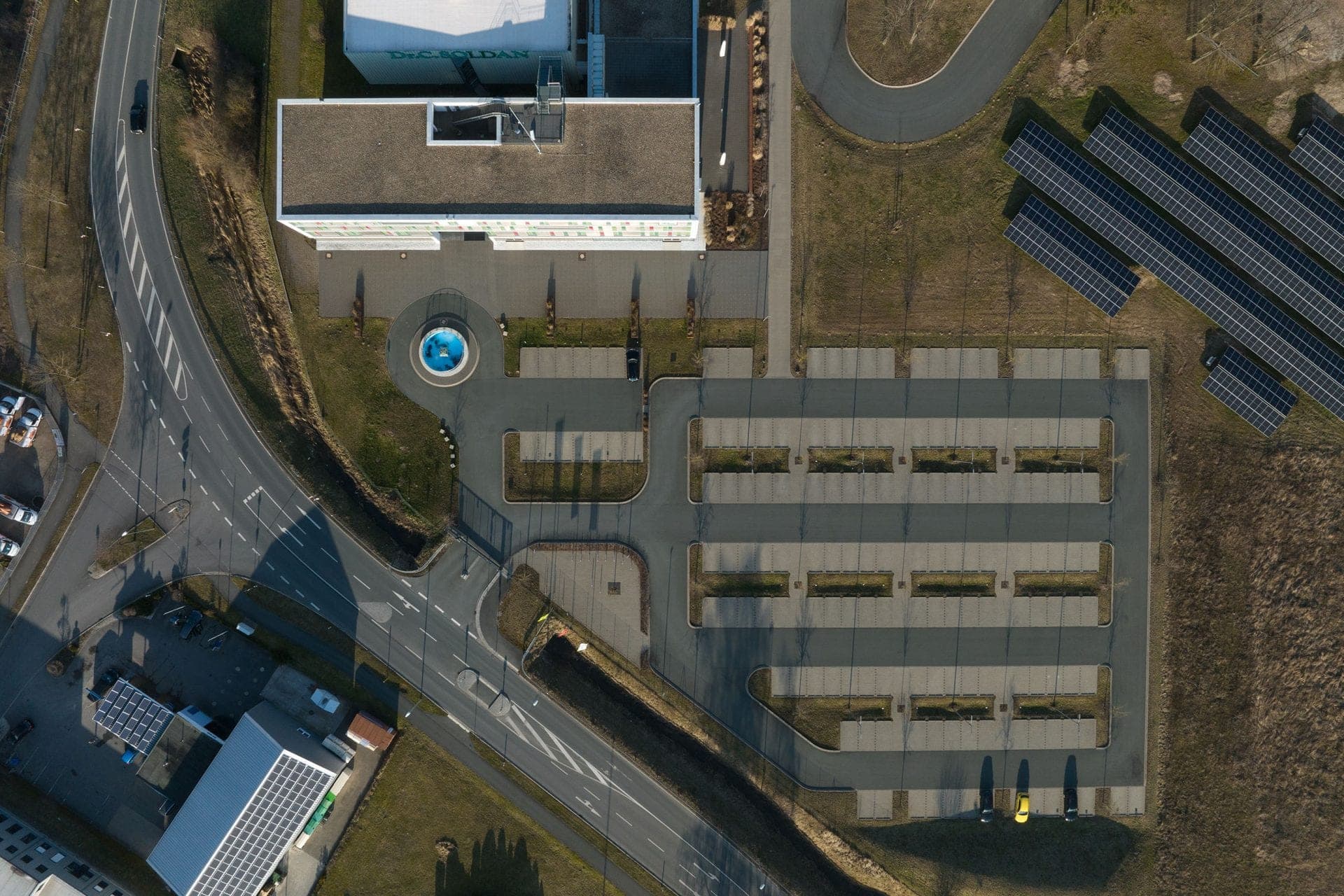 Vertical aerial view of the new building in Adelsdorf with turning circle, car park and neighbouring solar array