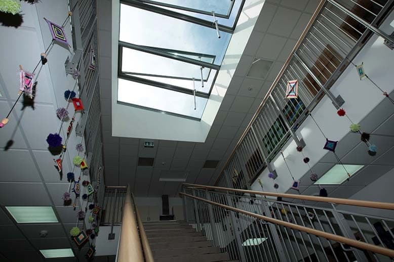 Blick nach oben in den Treppenraum mit Oberlicht und gebastelten Hängedekorationen an den Geländern