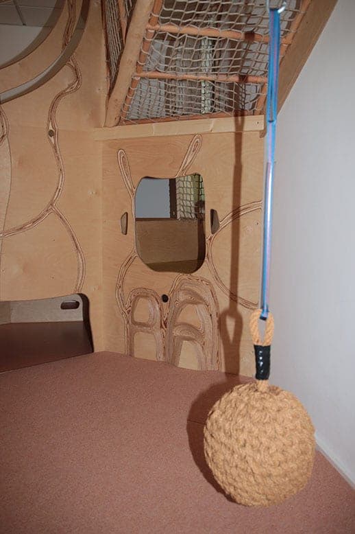 Nahaufnahme der Spiellandschaft aus Holz mit Netzboden, Durchguckloch und Seil mit Knotenball