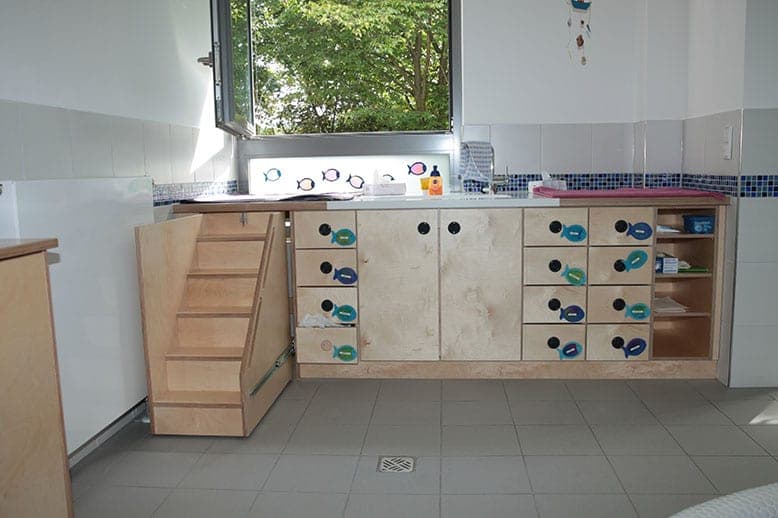 Wickelkommode aus Holz mit ausziehbarer Treppe und Schubladen mit Fischmotiven unter dem Fenster
