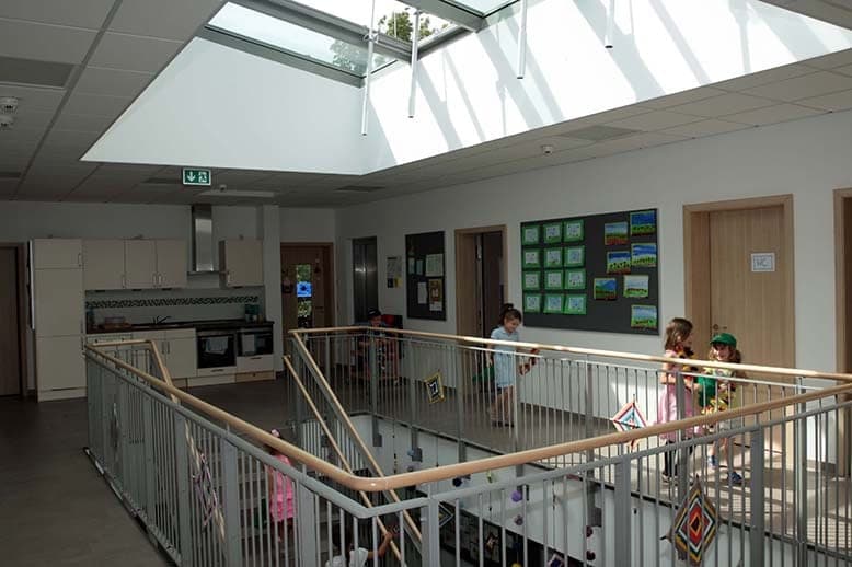 Galerie im Obergeschoss mit Oberlicht über der offenen Treppe, Infotafeln und spielenden Kindern