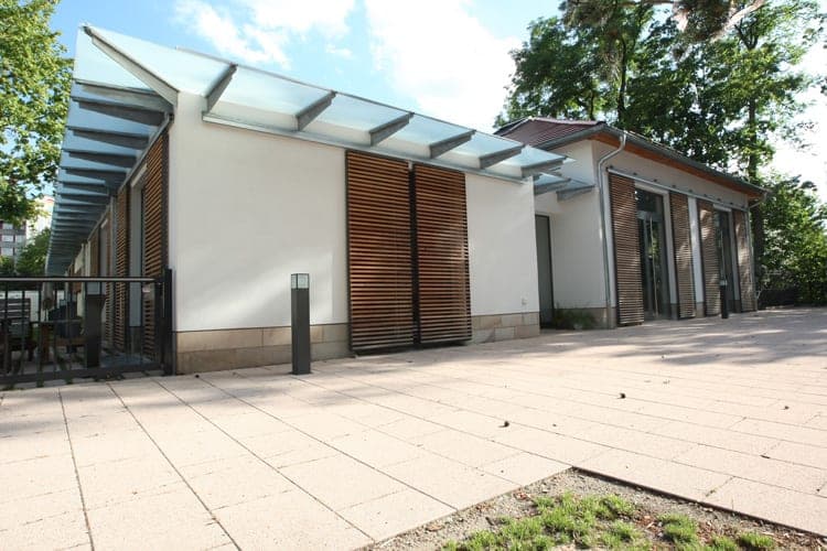 Terrace side of the wing with glass canopy and closed louvre shutters, the pavilion behind
