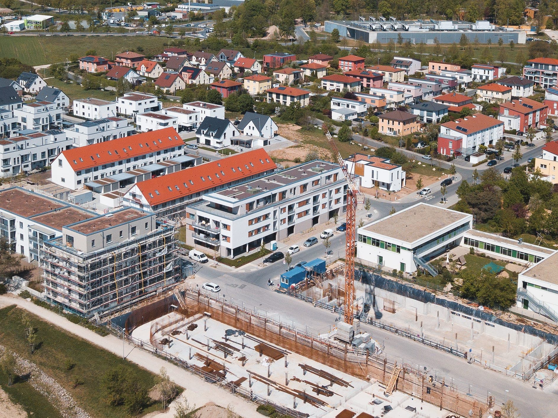Aerial view of Herzo Base with the completed residential building, neighbouring houses and an excavation with crane