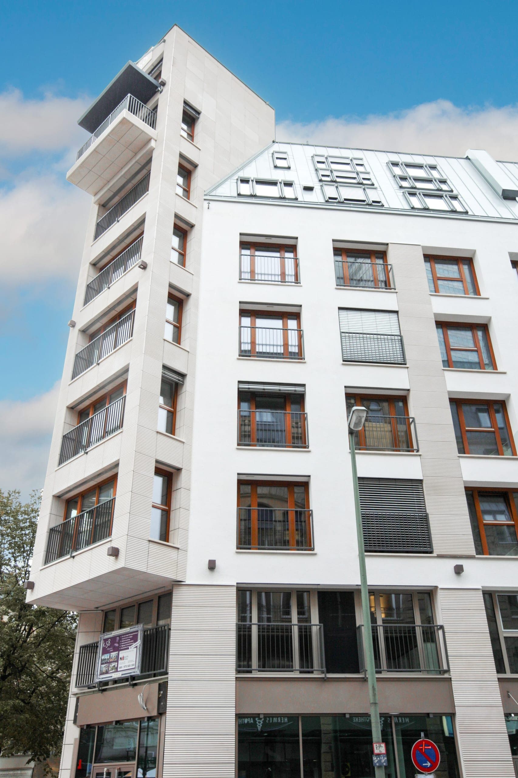 Eckturm des Wohn- und Geschäftshauses mit übereinanderliegenden Balkonen und Holzfenstern