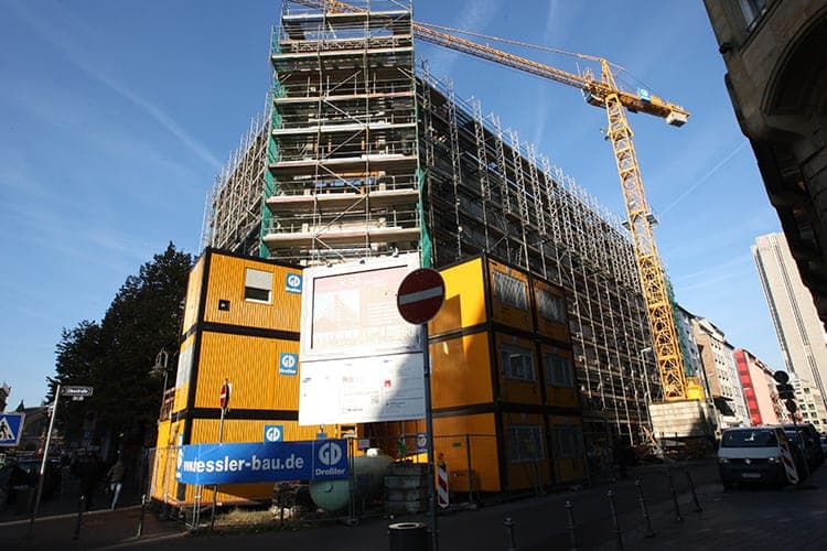 Baustelle an der Kaiserstraße mit eingerüstetem Gebäude, Turmkran und gestapelten Bürocontainern
