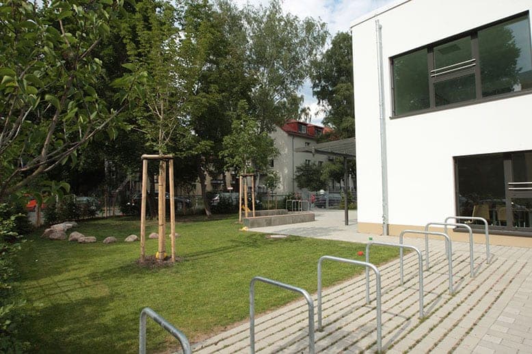 View across the bicycle racks to the lawn, young trees and the white corner of the day-care centre in Nuremberg