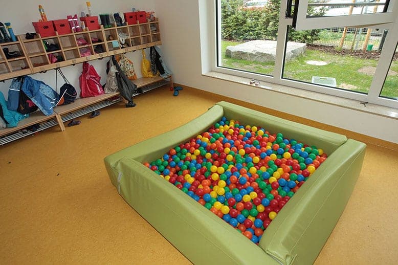Ball pit in the cloakroom area with cubbies for coats and bags, with a window view into the garden