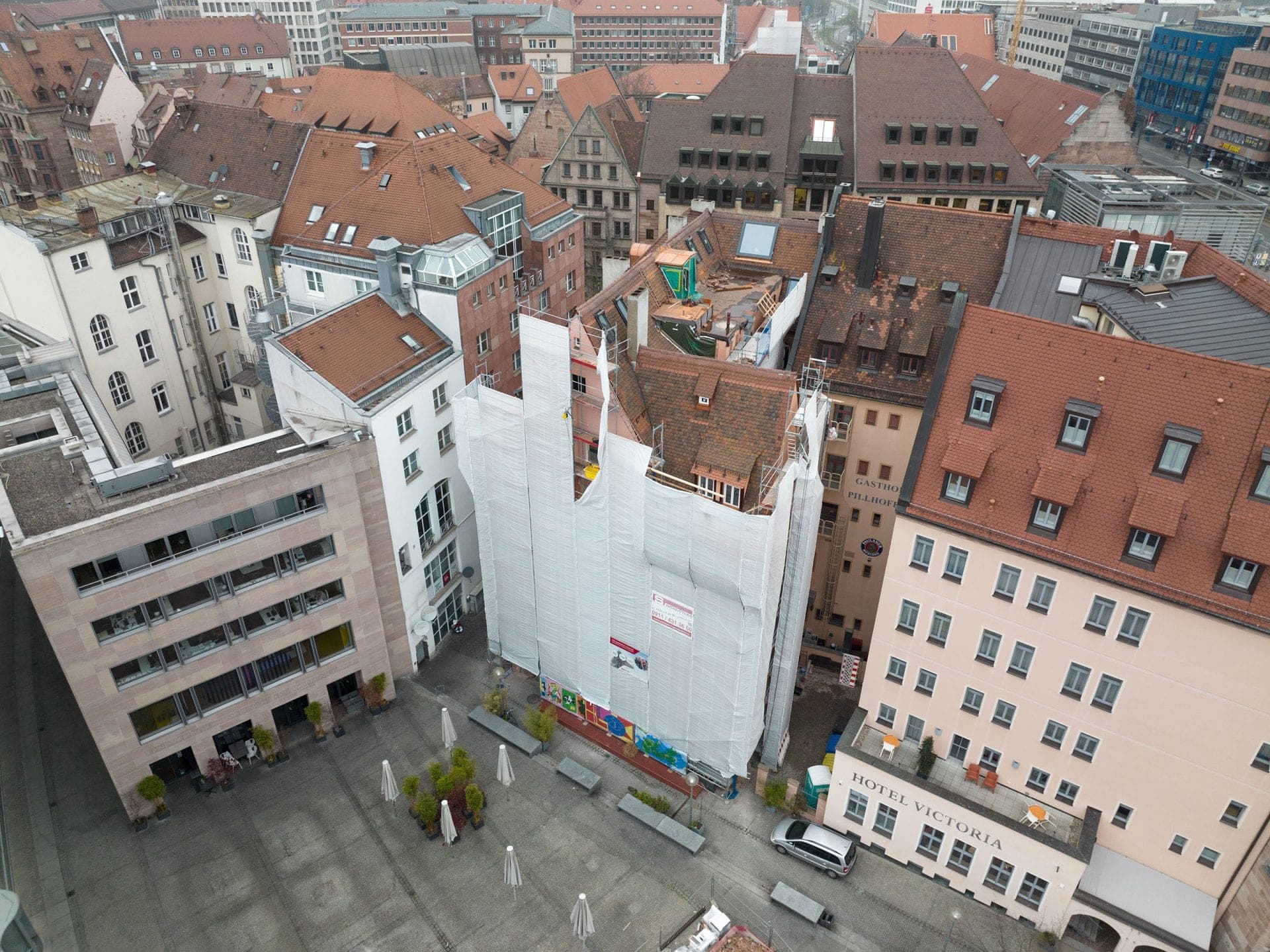 Aerial view of the scaffolded and sheeted building during refurbishment on Klarissenplatz