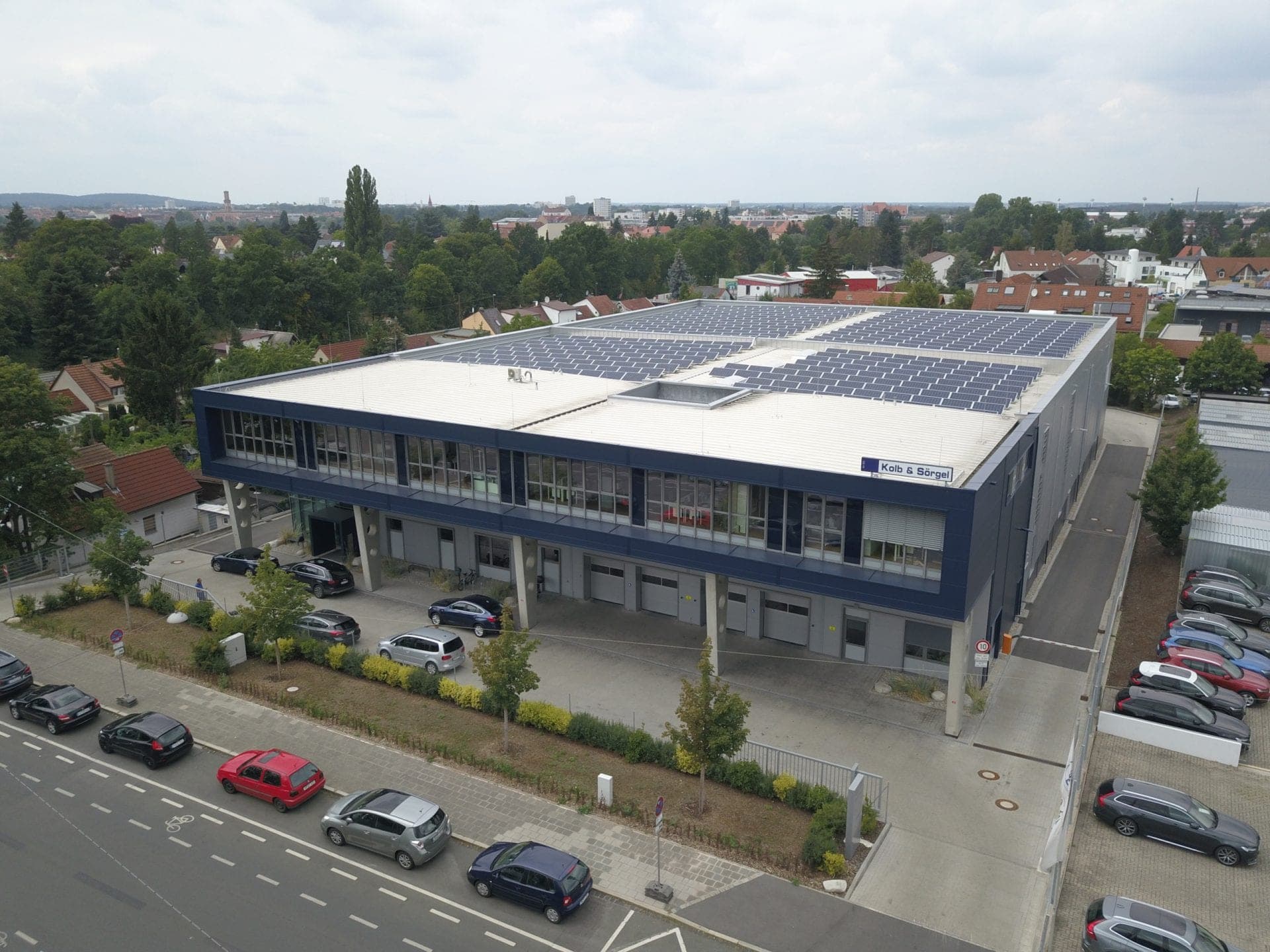 Aerial view of the new building on the street with the dark blue clad office floor and trees beyond