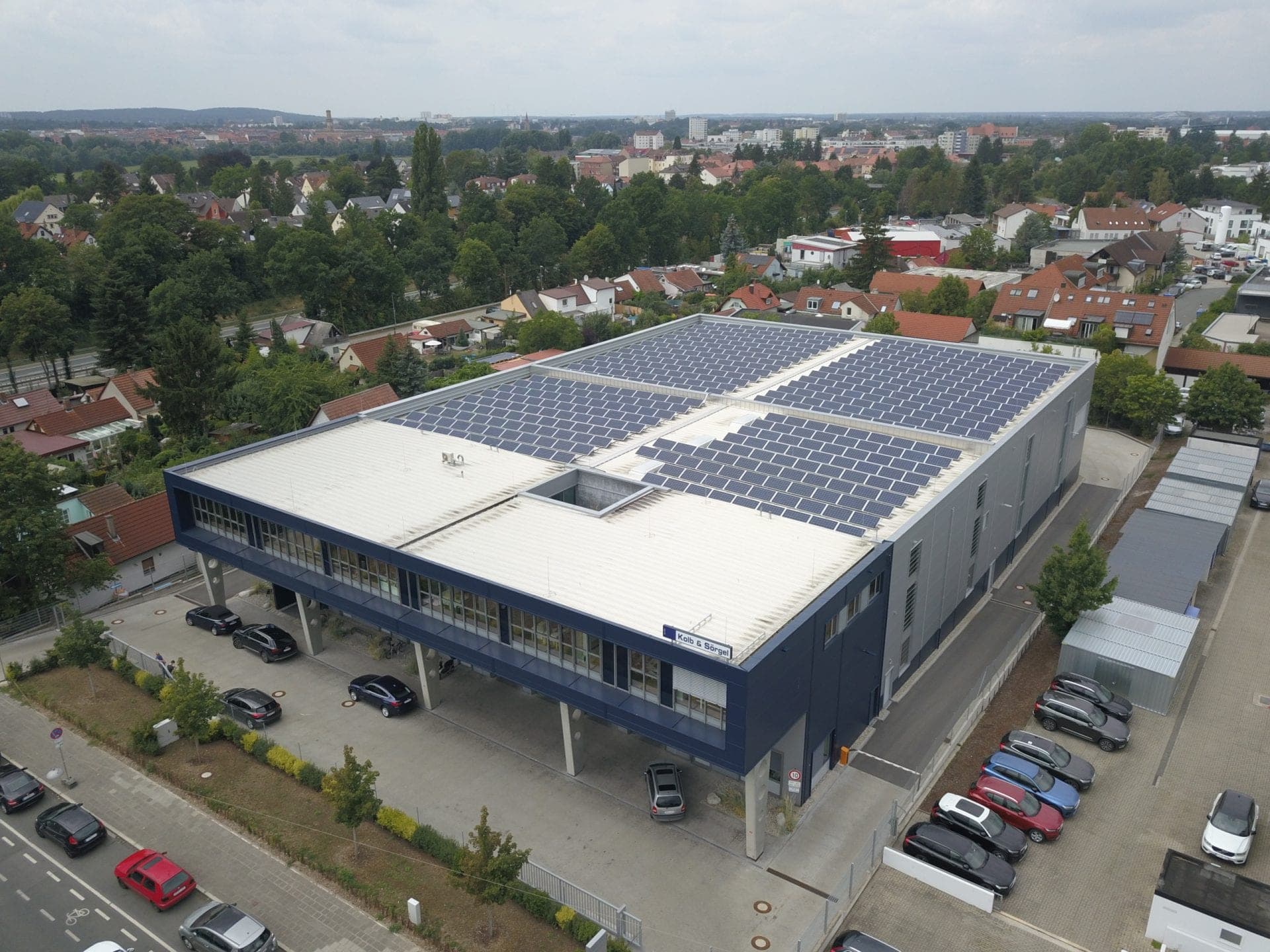 Oblique aerial view of the roof with its photovoltaic array and courtyard cut-out, with Fürth beyond