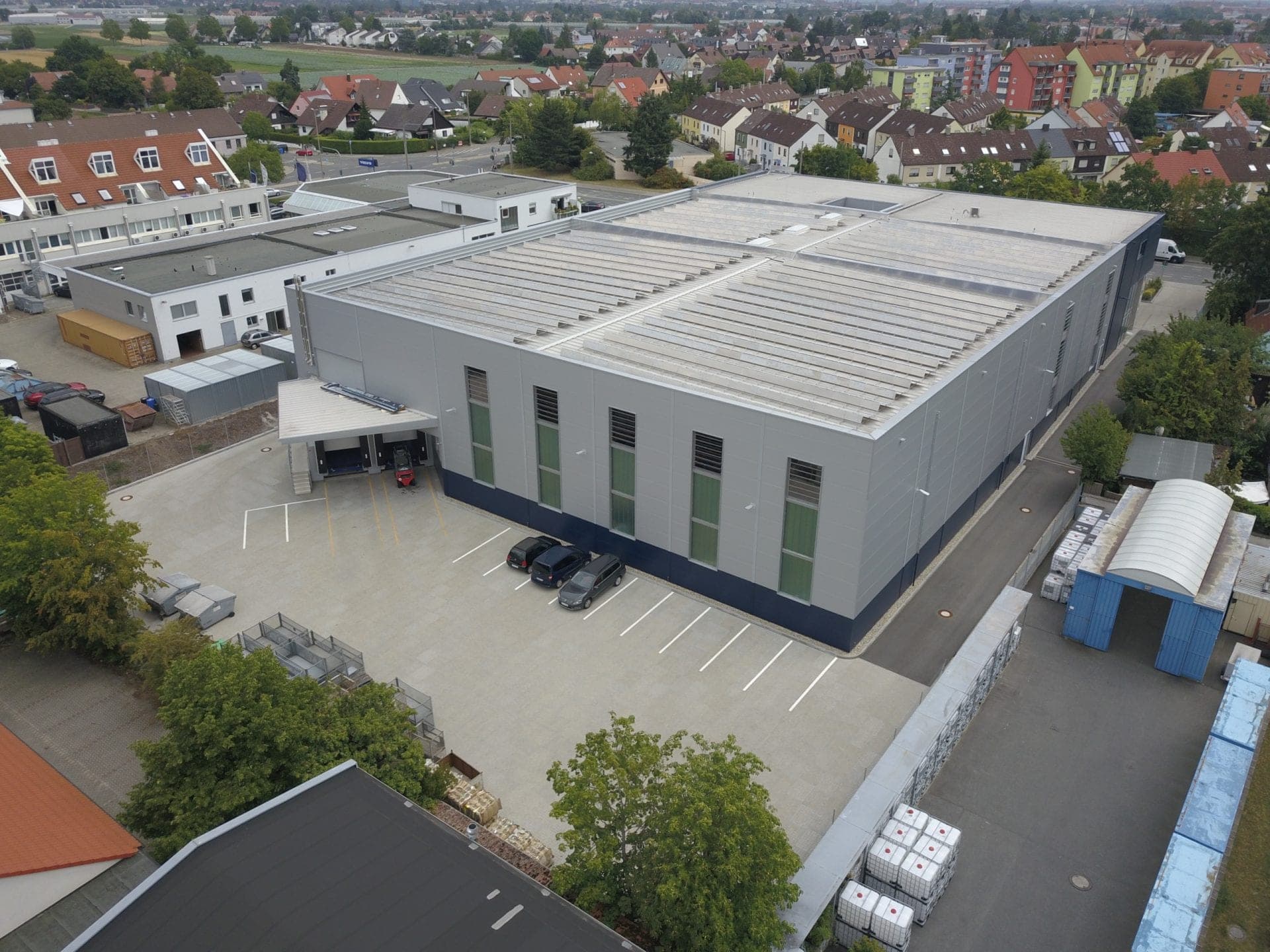 Aerial view of the delivery area with a covered loading dock, parking spaces and the grey hall façade