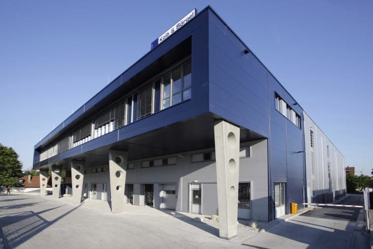 Dark blue façade with Kolb & Sörgel lettering and the office floor cantilevered on slender concrete columns