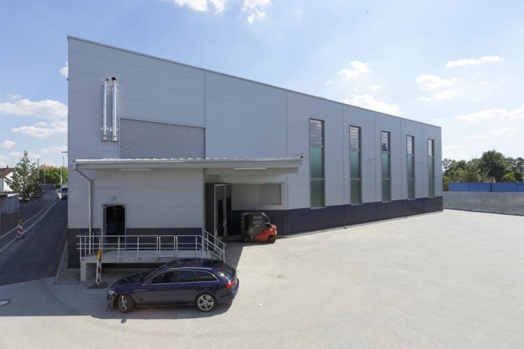 Side view of the warehouse with the covered loading dock, a forklift and tall vertical window strips
