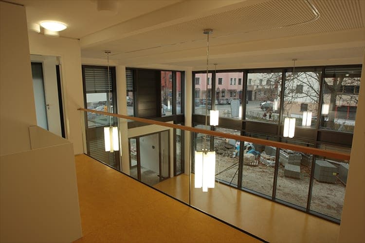 Galerie mit Glasbrüstung über einem zweigeschossigen Raum und raumhoher Verglasung zur Straße
