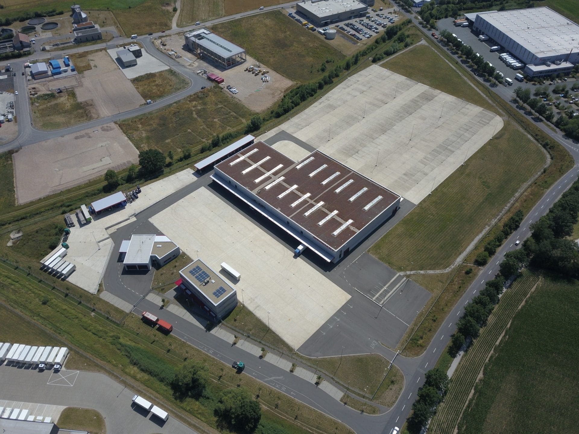 Steep aerial view of the logistics hall with rooflight strips, the workshop and the office building