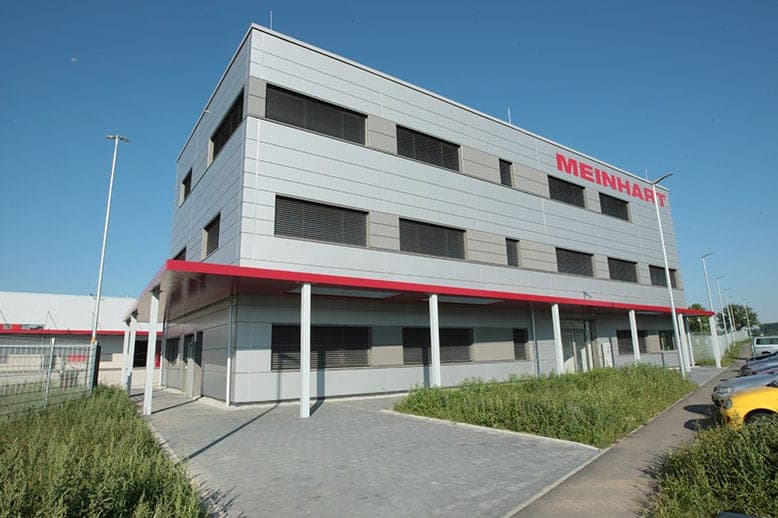 Office building of the logistics centre with grey panel façade, red canopy edge and company lettering