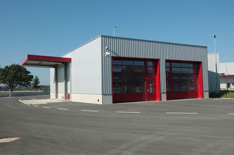Workshop building with two red doors and a side canopy with a red edge