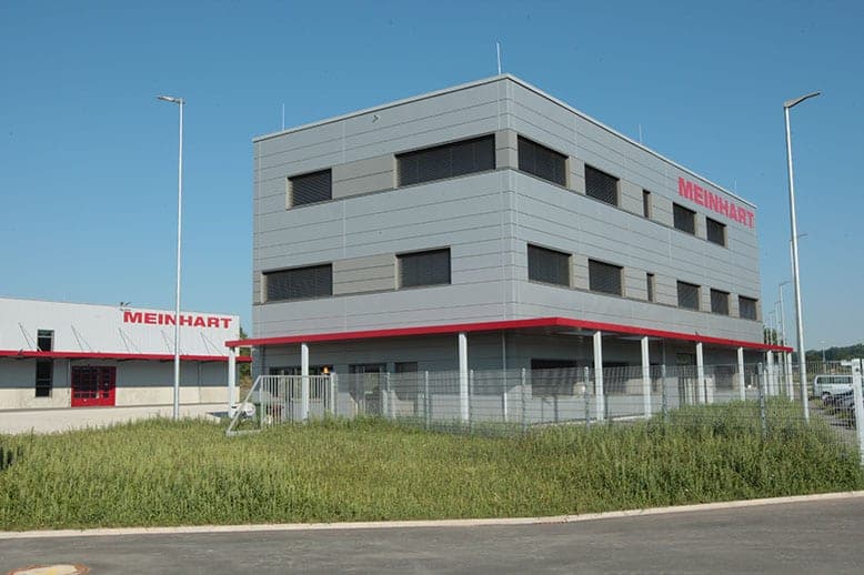 Three-storey office building with window bands, company lettering and a canopy on slender columns