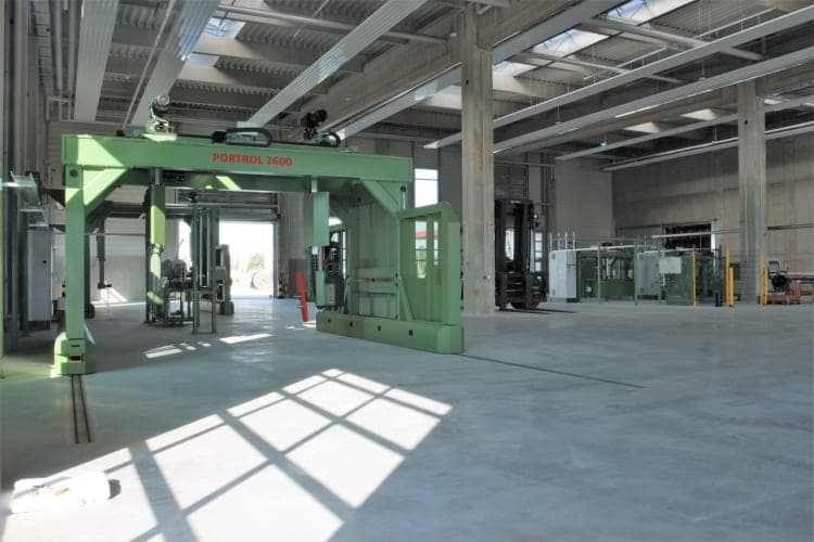 Hall area with a green gantry machine, concrete columns and rooflights