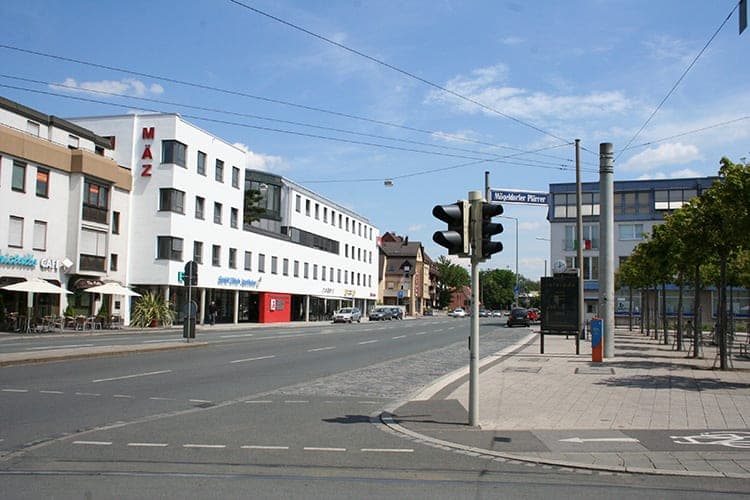 Straßenkreuzung am Mögeldorfer Plärrer mit Ampel, Gleisen und dem weißen Neubau im Hintergrund